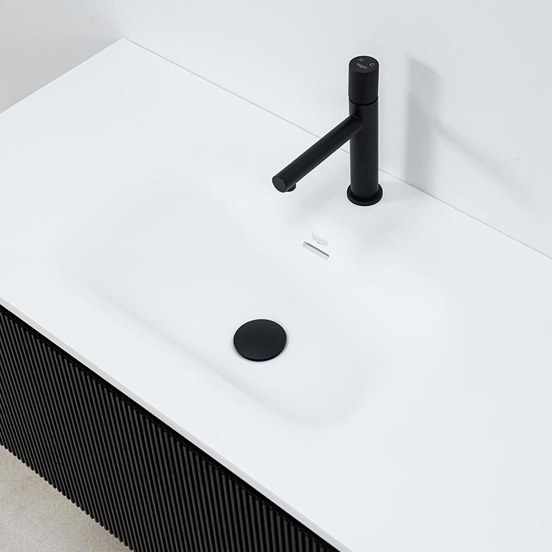 Minimalistiskt vitt helgjutet tvättställ i stenkomposit med svart blandare