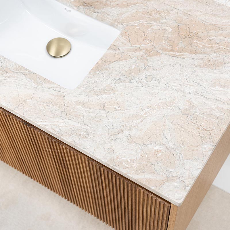 Tvättställ i beige marmor och bottenventil i mässing